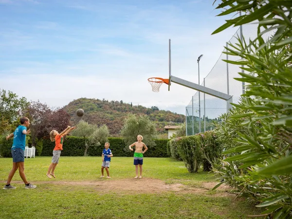 Kinder spielen Basketball auf dem Roan-Campingplatz La Rocca Manerba.