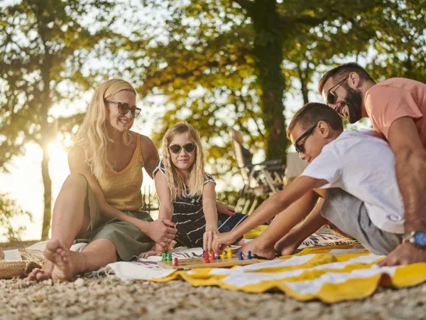 Eine Familie spielt ein Brettspiel auf dem Roan-Campingplatz Zelena Laguna.