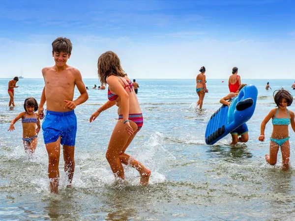 Kinder spielen im Meer auf dem Campingplatz Roan Sole Family Camping Village.