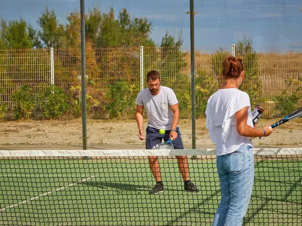2 Personen spielen eine Partie Tennis auf dem Campingplatz Roan Les Dunes.