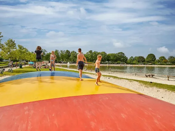 Airtrampolin mit hüpfenden Kindern am Strand auf dem Roan Camping Terspegelt.