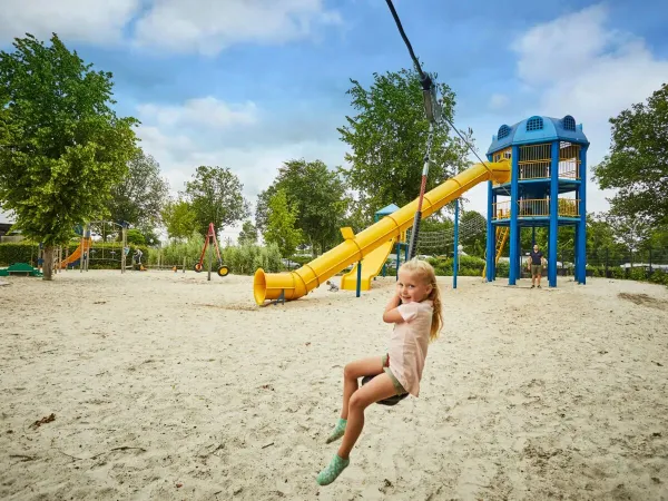 Mädchen auf der Seilbahn auf dem großen Spielplatz des Roan Camping Terspegelt.