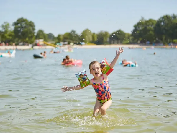 Glückliches Mädchen im Schwimmbad auf dem Roan Camping Terspegelt.