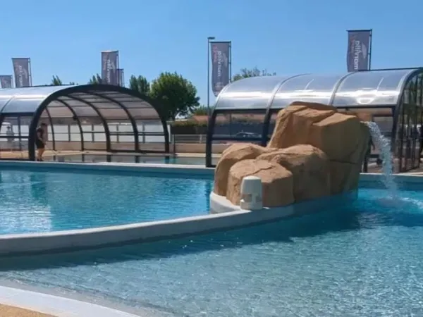 Überdachtes Schwimmbad und Freibad mit Wasserfall auf dem Campingplatz Le Domaine du Clarys in Roan.