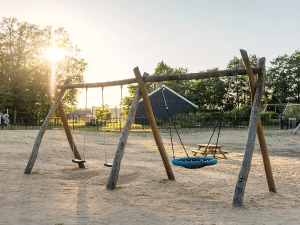 Der Sandspielplatz mit Schaukeln auf dem Roan Camping de Twee Bruggen.