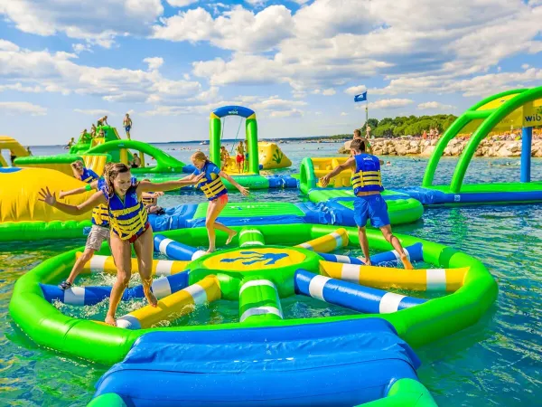 Kinder spielen auf Luftkissen im See auf dem Campingplatz Le Lac des Vieilles Forges in Roan.